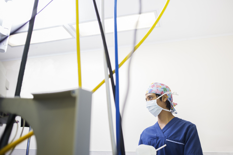 Junge Krankenschwester kontrolliert medizinische Geräte während einer Operation, lizenzfreies Stockfoto