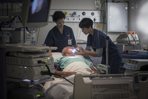 Reife Ärztin und Krankenschwester untersuchen den Rachen eines Patienten - CAIF17492