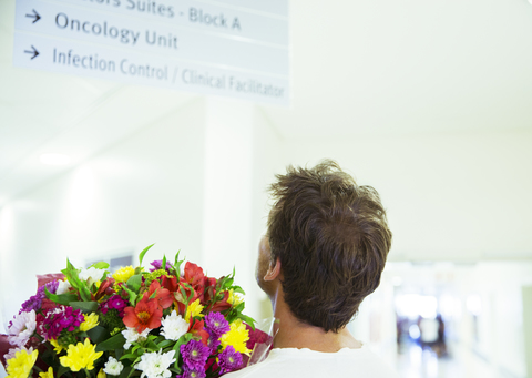 Mann mit Blumenstrauß im Krankenhaus, lizenzfreies Stockfoto