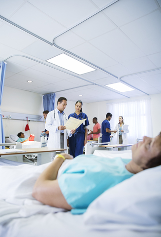 Arzt und Krankenschwester lesen Krankenblatt im Krankenhauszimmer, lizenzfreies Stockfoto