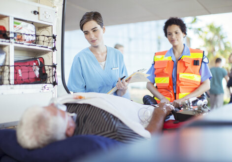 Paramedic and nurse examining patient in ambulance - CAIF17511
