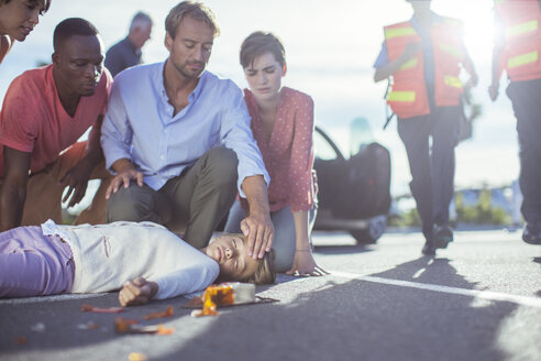 Menschen untersuchen ein verletztes Mädchen auf der Straße - CAIF17522