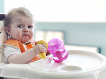 Baby girl playing with sippy cup in high chair - CAIF17556