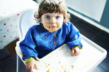 Unordentliches Babymädchen beim Essen im Hochstuhl - CAIF17557