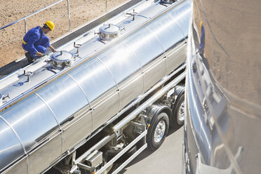 Arbeiter auf einer Plattform über einem Milchtankwagen aus rostfreiem Stahl - CAIF17593