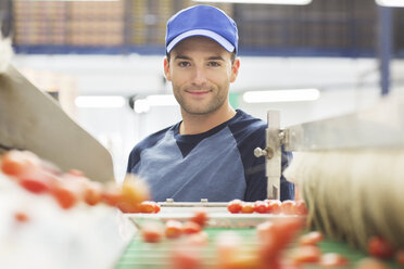 Porträt eines Arbeiters am Förderband in einem Lebensmittelverarbeitungsbetrieb - CAIF17609