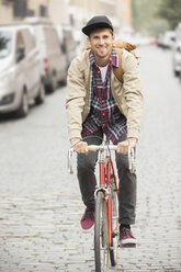 Man riding bicycle on city street - CAIF17663