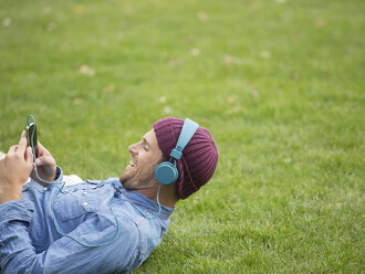 Man listening to headphones in park - CAIF17666