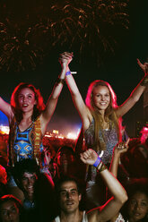 Jubelnde Frauen auf den Schultern von Männern beim Musikfestival - CAIF17672