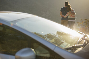 Couple hugging outside car at roadside - CAIF17673