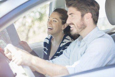 Happy couple with map driving in car - CAIF17686