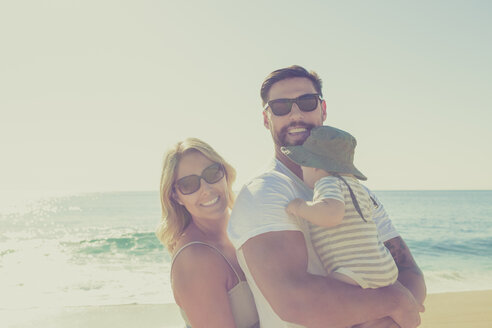 Porträt einer glücklichen Familie am sonnigen Strand - CAIF17697