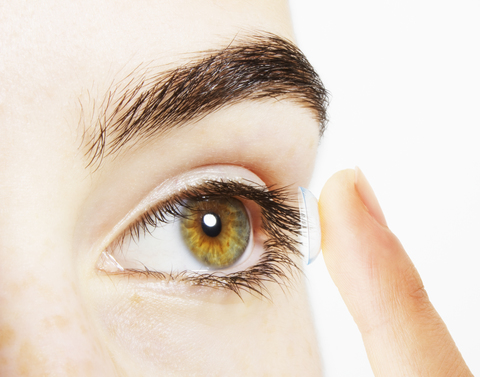 Extreme Nahaufnahme einer Frau, die eine Kontaktlinse ins Auge setzt, lizenzfreies Stockfoto