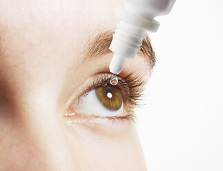 Extreme Nahaufnahme einer Frau, die Augentropfen in ein Auge einführt - CAIF17714