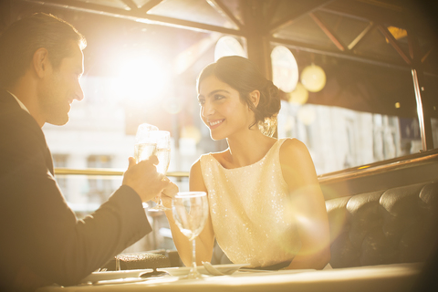 Paar stößt in einem Restaurant mit Champagnerflöten an, lizenzfreies Stockfoto