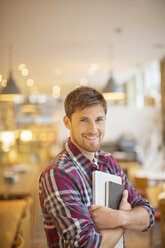 Mann hält Bücher in einem Café - CAIF17751