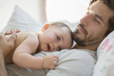 Vater liegt mit Baby auf dem Bett - CAIF17777