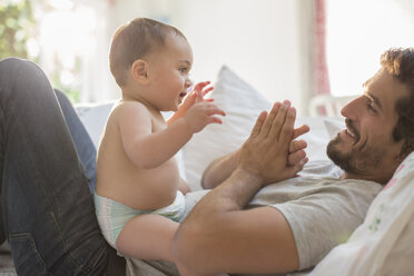 Vater spielt mit kleinem Jungen auf dem Bett - CAIF17783