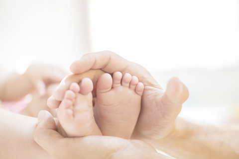 Vater wiegt die Füße des kleinen Jungen, lizenzfreies Stockfoto