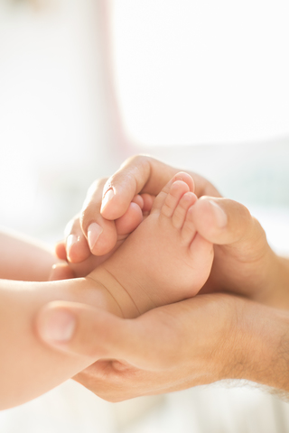 Vater wiegt die Füße des kleinen Jungen, lizenzfreies Stockfoto