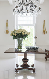 Kronleuchter über dem Blumenstrauß auf dem Tisch im luxuriösen Foyer - CAIF17821