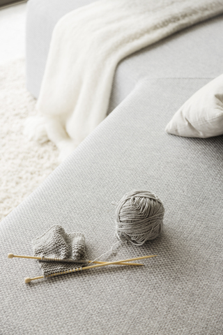 Stricknadeln und Wollknäuel auf dem Sofa, lizenzfreies Stockfoto