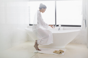 Woman in bathrobe preparing bath - CAIF17882