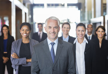 Business people smiling in lobby - CAIF17912