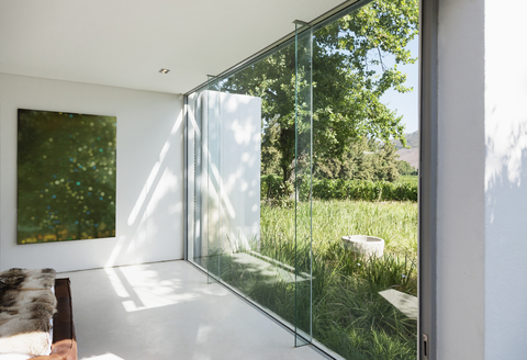 Modernes Haus mit Glaswänden und Blick auf die Wiese, lizenzfreies Stockfoto