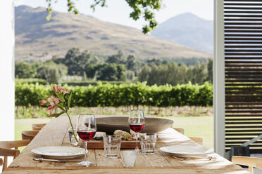 Dining table and chairs on luxury patio overlooking vineyard - CAIF17983