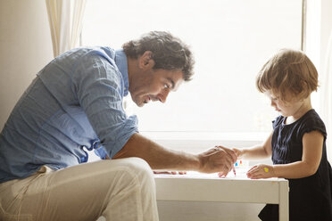 Father teaching daughter coloring at table in home - CAVF09181