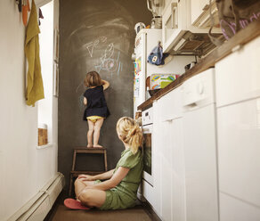 Tochter schreibt an die Wand, Mutter sitzt zu Hause - CAVF09186