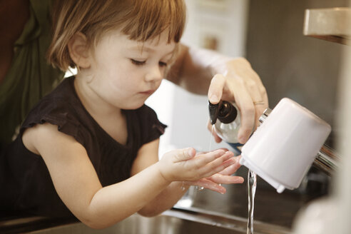 Ausgeschnittenes Bild einer Mutter, die ihrer Tochter beim Händewaschen zu Hause hilft - CAVF09189