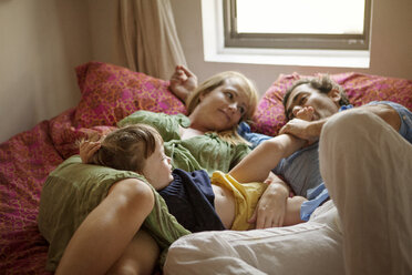 Familie auf dem Bett liegend zu Hause - CAVF09194