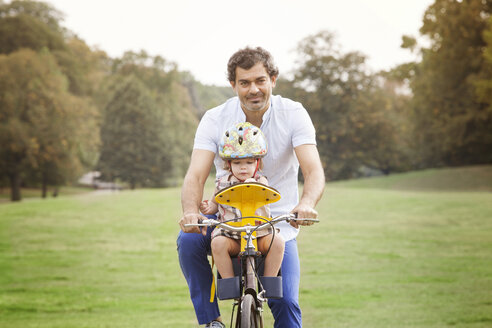 Vater mit Tochter beim Fahrradfahren im Park - CAVF09218