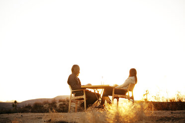 Low angle view of couple sitting on chairs against clear sky - CAVF09336