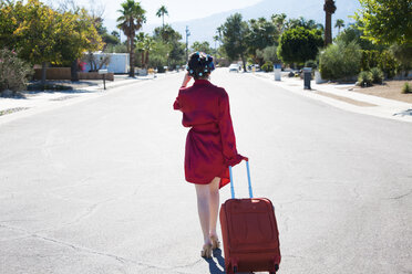 Rückansicht einer Frau mit Koffer auf der Straße - CAVF09389