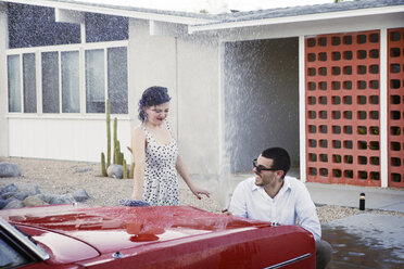 Verspieltes Paar beim Autowaschen auf einem Parkplatz - CAVF09417