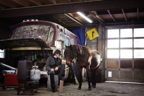 Mann mit Pferd in der Werkstatt sitzend - CAVF09491