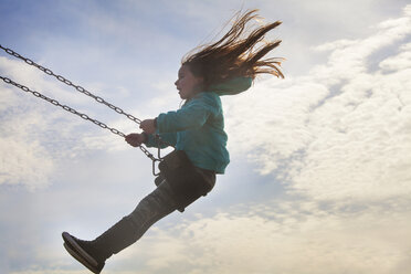 Side view of girl swinging against cloudy sky - CAVF09520