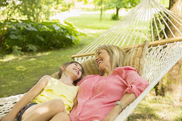 Grandmother and granddaughter relaxing in hammock - CAIF17996