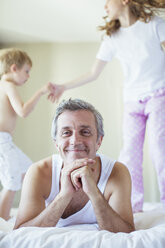 Kinder springen auf dem Bett um den Vater herum - CAIF18008