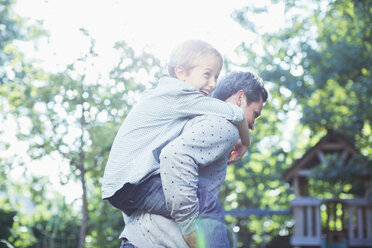 Father carrying son piggyback outdoors - CAIF18009