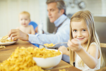 Girl eating overflowing bowl of cereal - CAIF18023