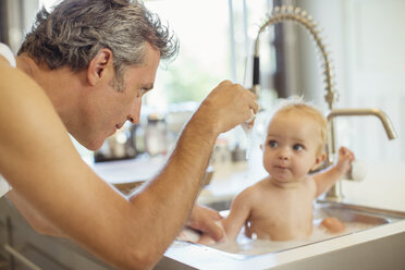 Vater badet Baby in Küchenspüle - CAIF18029