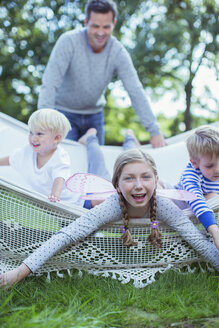 Vater schiebt Kinder in Hängematte im Freien - CAIF18036