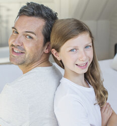 Father and daughter smiling in bedroom - CAIF18039