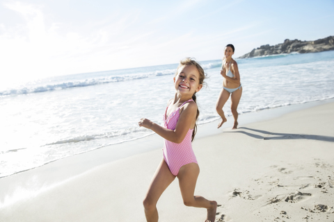Mutter und Tochter laufen am Strand, lizenzfreies Stockfoto