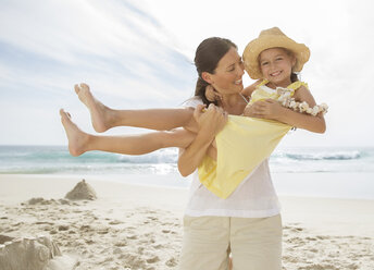 Mother holding daughter on beach - CAIF18051