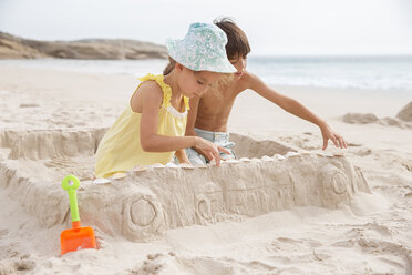 Children making sandcastle on beach - CAIF18053